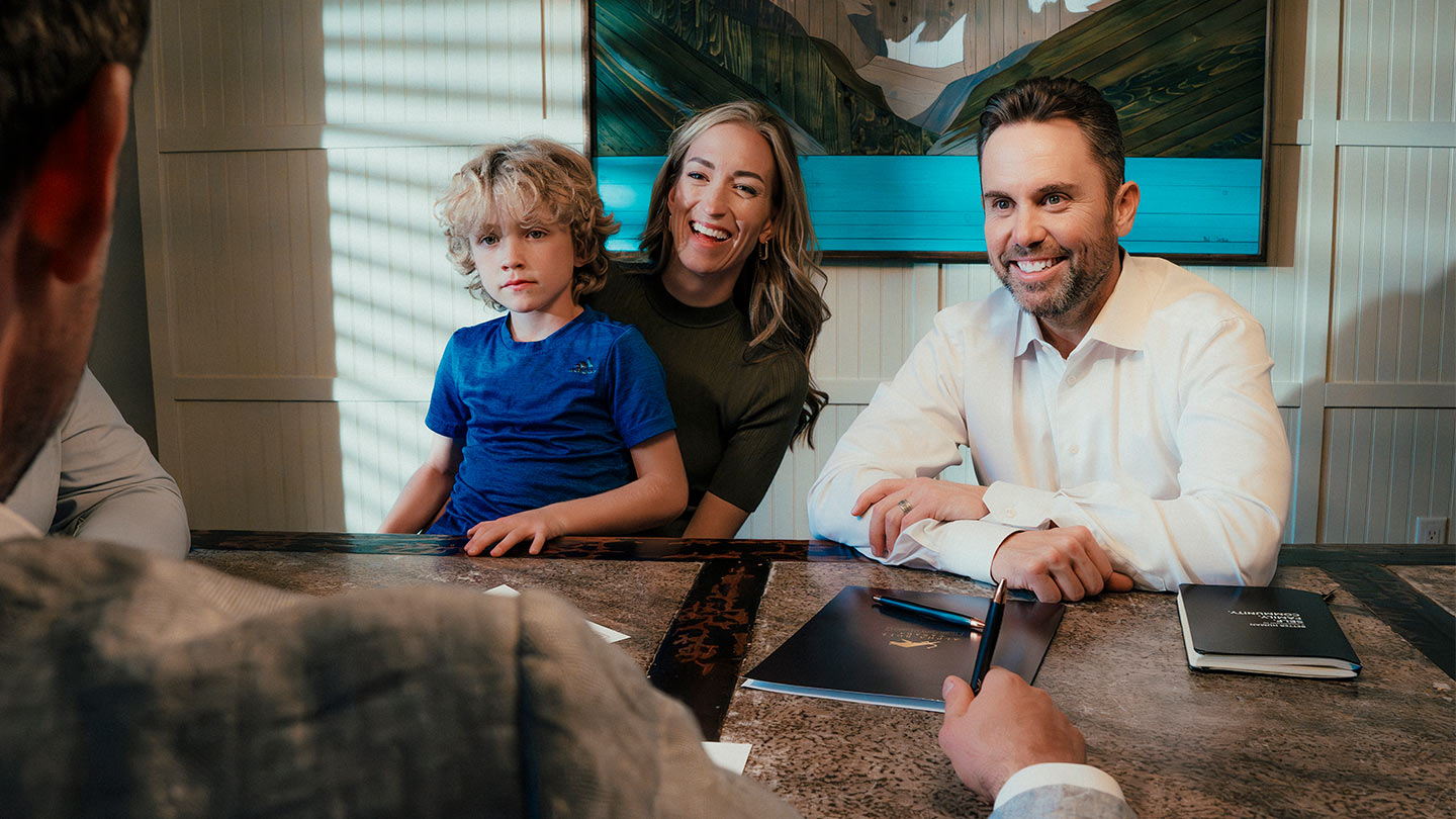 Happy family meeting with financial advisor in a professional setting. Smiling parents and young child listening attentively as advisor discusses planning and strategy, highlighting a family-oriented financial consultation.
